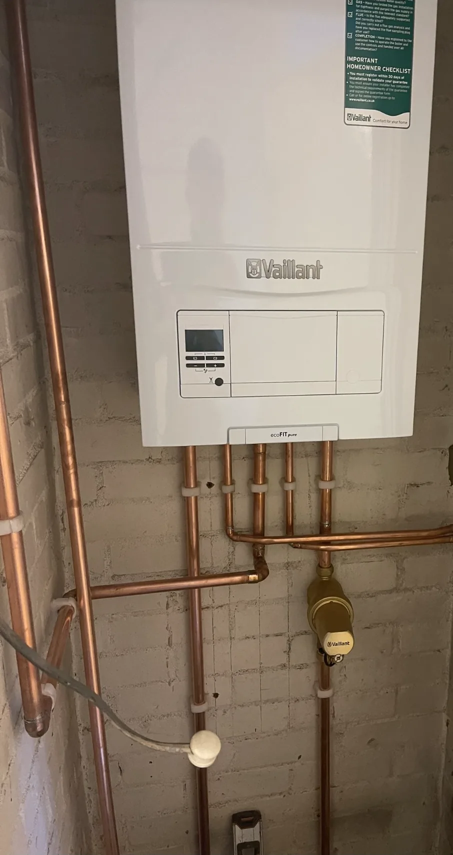A Vaillant combi boiler installed on a utility wall with new copper flow and return pipework.