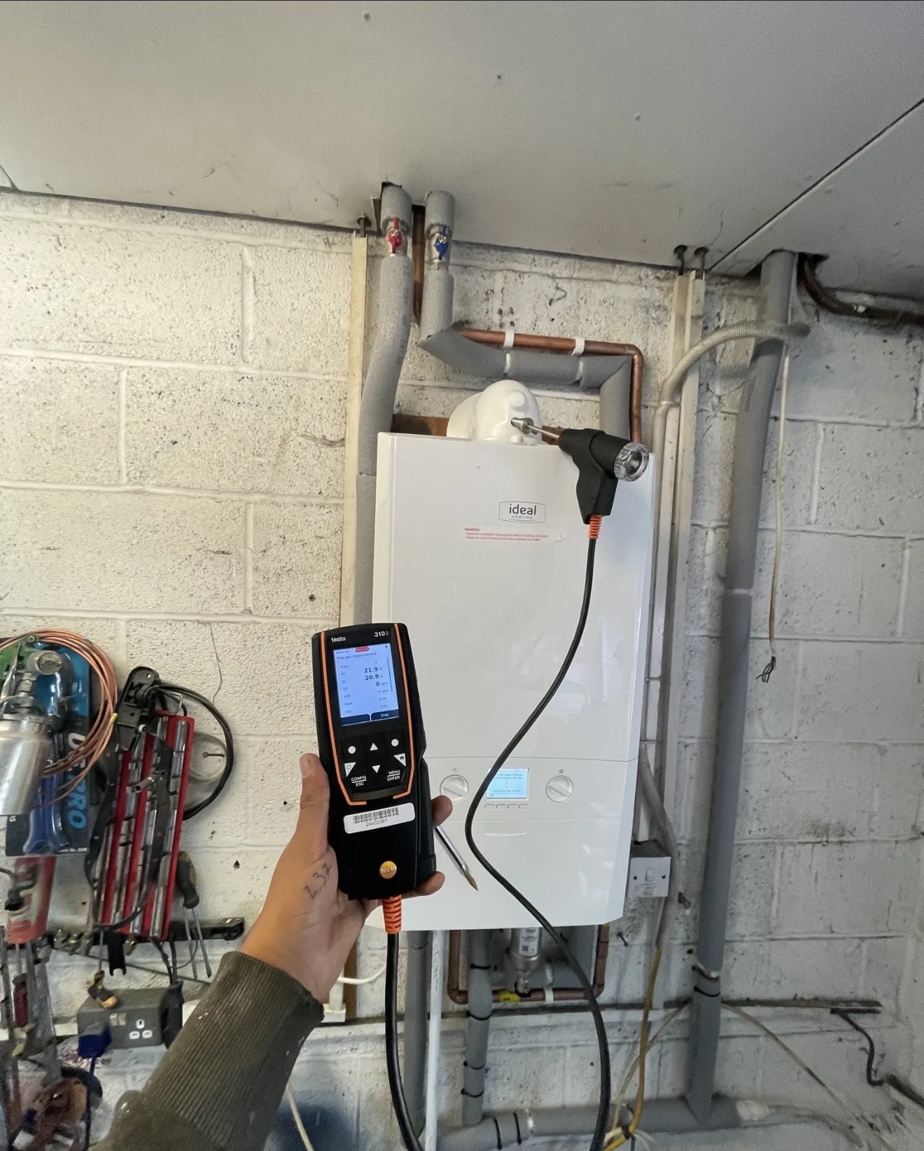 An engineer taking a flue gas analyser reading while servicing a boiler