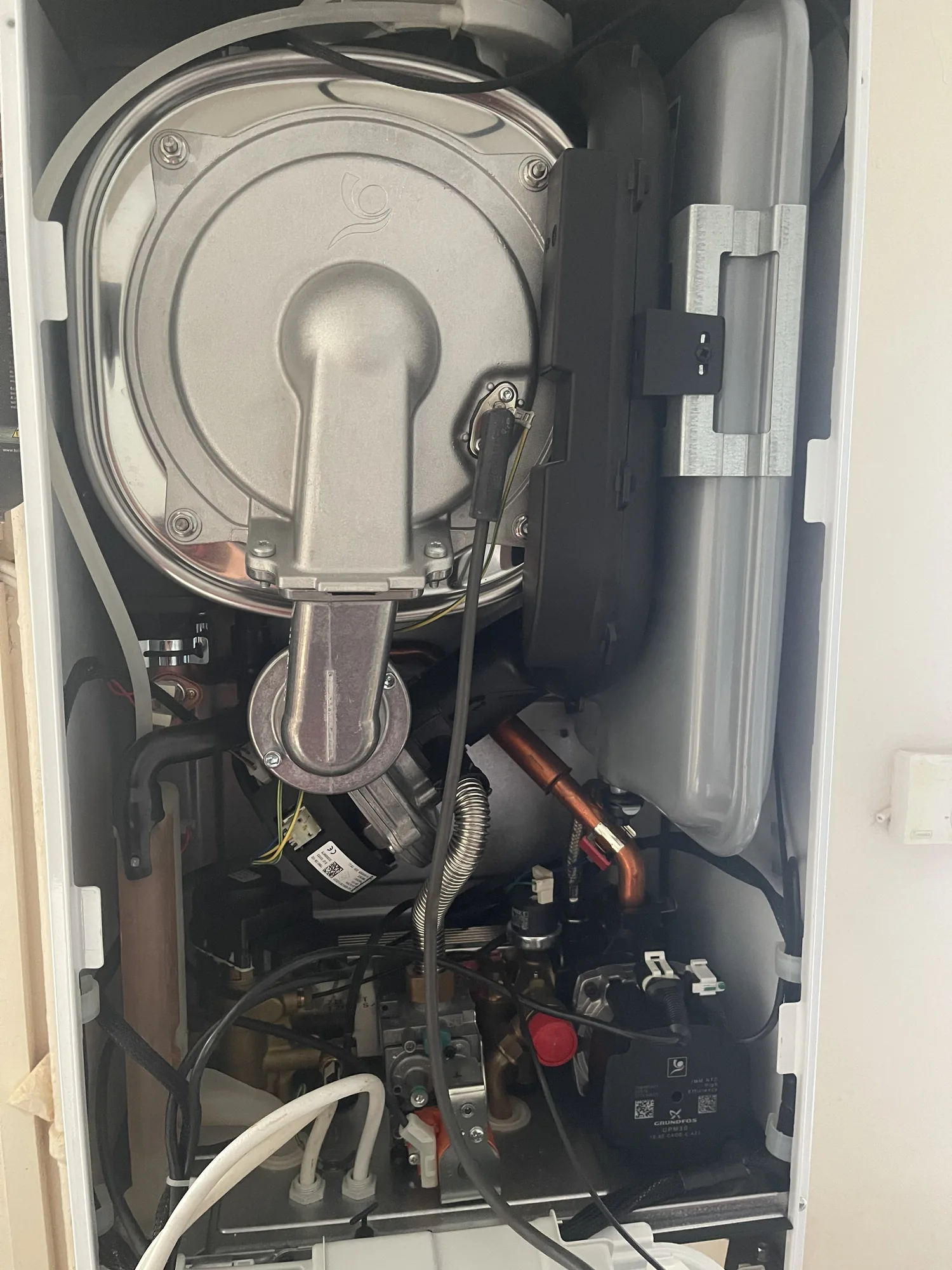 The internal components of a boiler exposed for an annual service, including the sealed combustion chamber and fan.